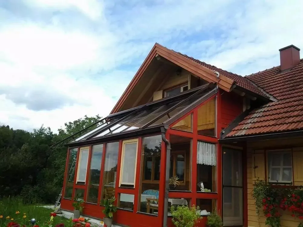 Rot gestrichener Holz-Wintergarten an einem Holzhaus