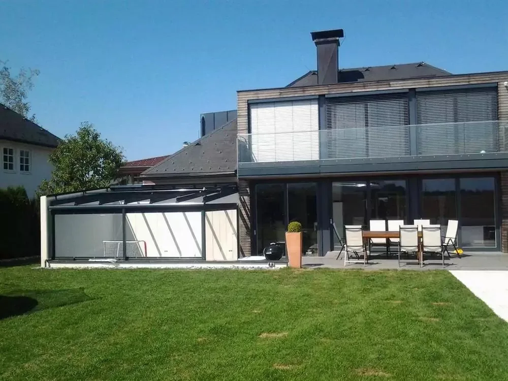 Terrassendach mit Glaswänden an einem modernen Haus mit Rasen