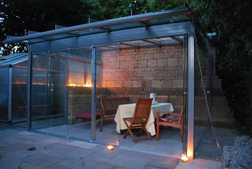 Glashaus am Abend mit gedecktem Tisch und Kerzenlicht