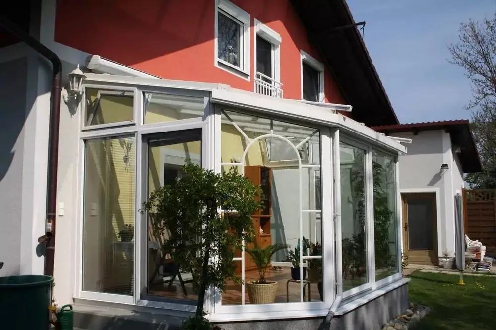 Weißer Wintergarten mit Bogensprossen an einem roten Haus