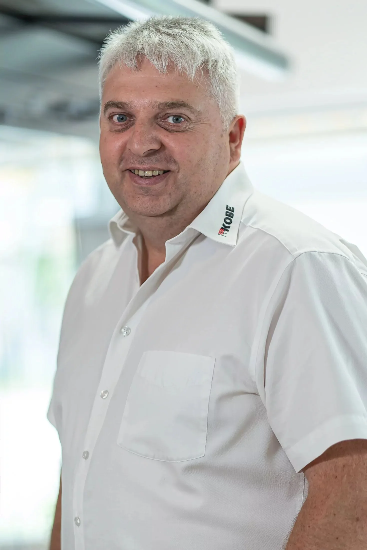Robert Kobencic im weißen KOBE-Hemd vor hellem Hintergrund